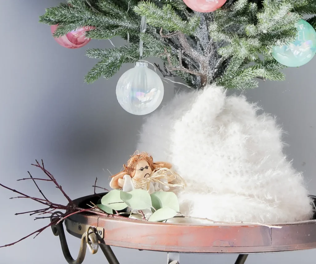 Small table top Christmas Tree on a table with a scarf as the tree skirt.