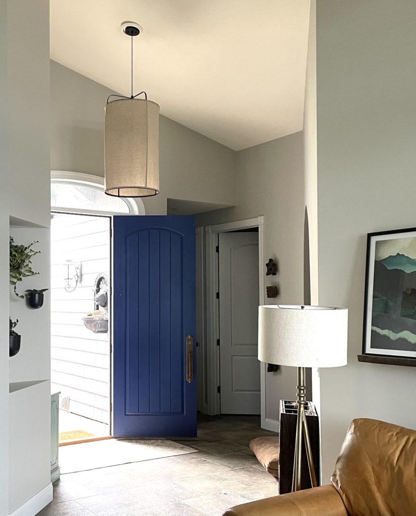 Entryway with painted blue door and pendant light.