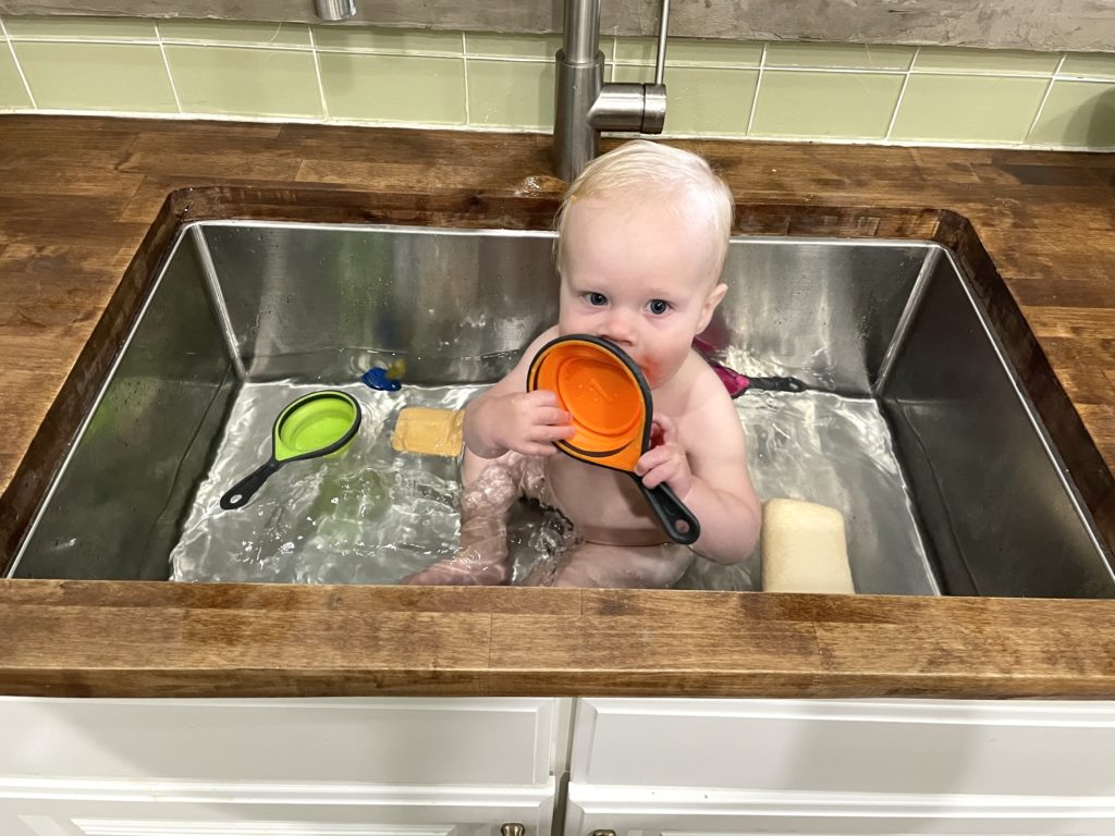 Baby in the sink showing stained butcher block counters