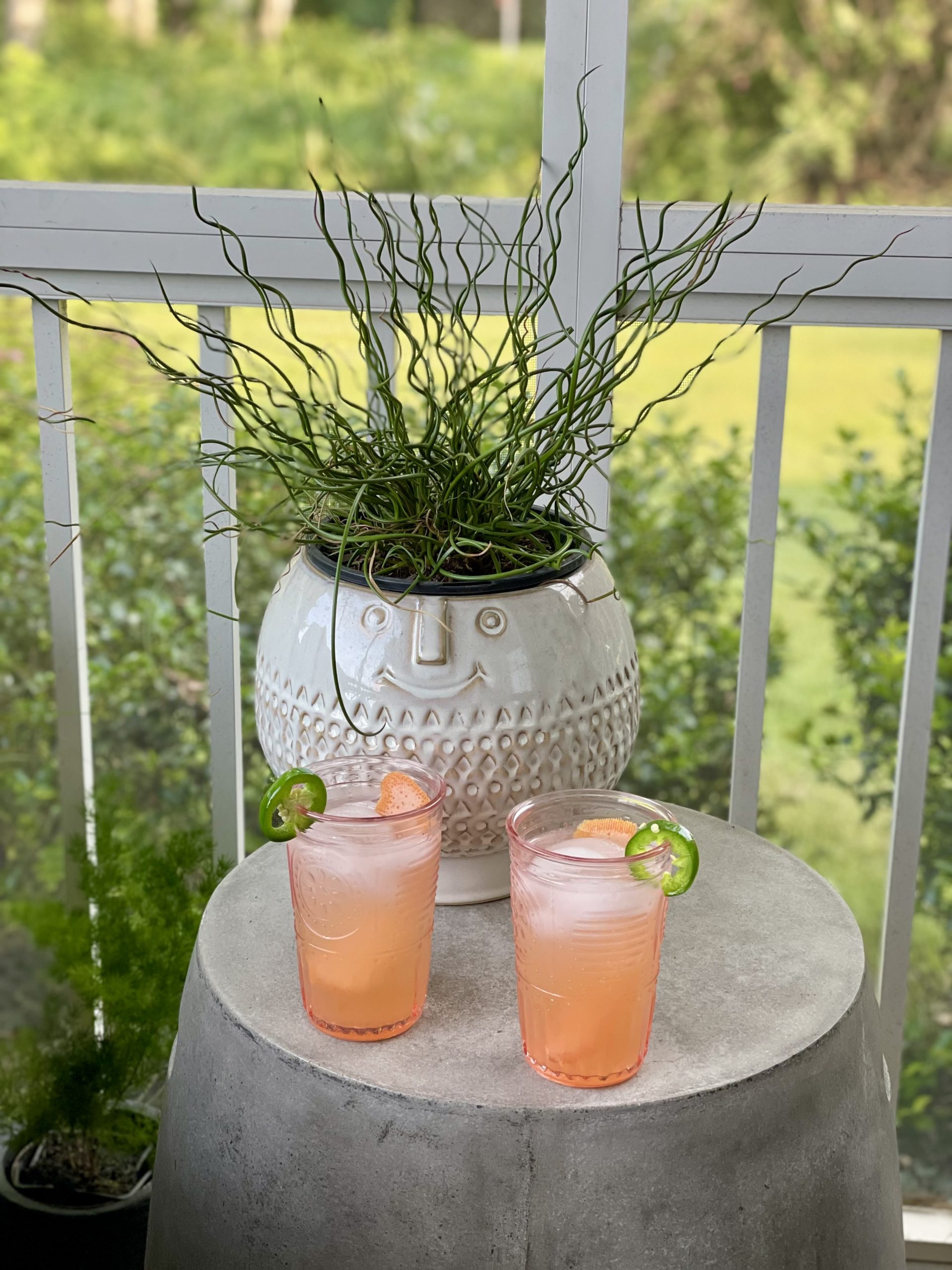 Porch setting with pretty Spicy Garden Cocktail sitting on concrete table