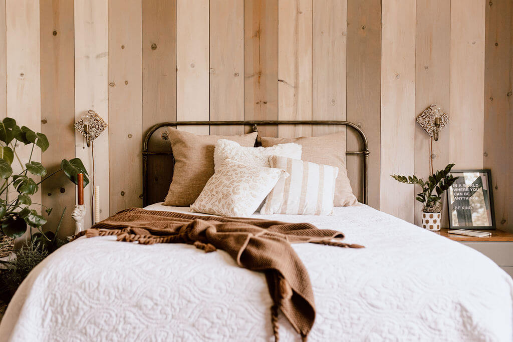 Cozy Fall Bedroom with Wood wall and bed made with neutral Fall colors and cozy textiles.