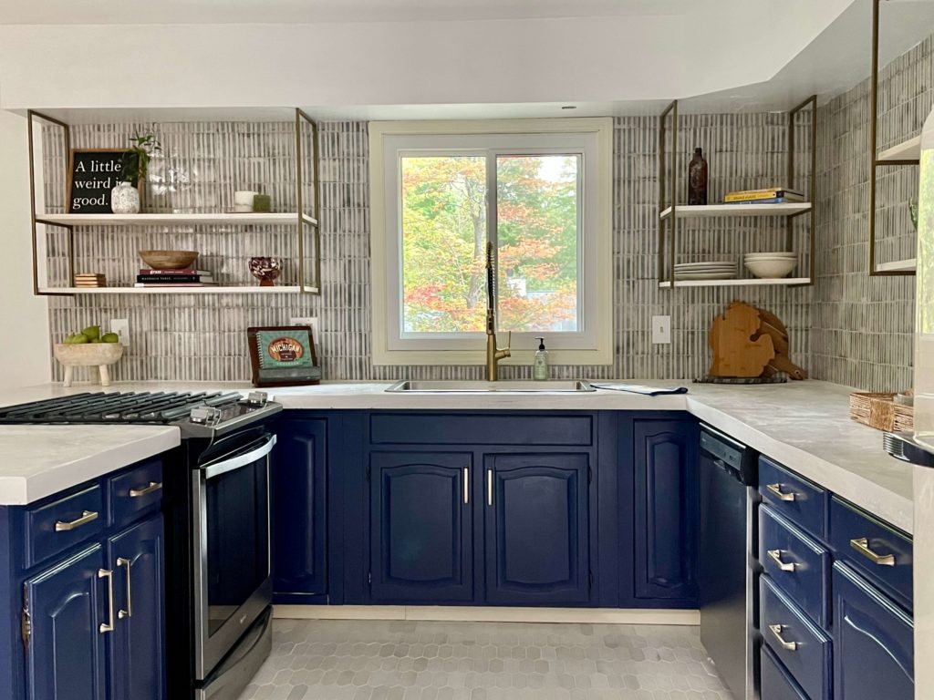 Navy painted cabinets with white concrete countertops and open shelving. Blue and white tile by Jeffery Court HD completes a Modern Cottage Kitchen.