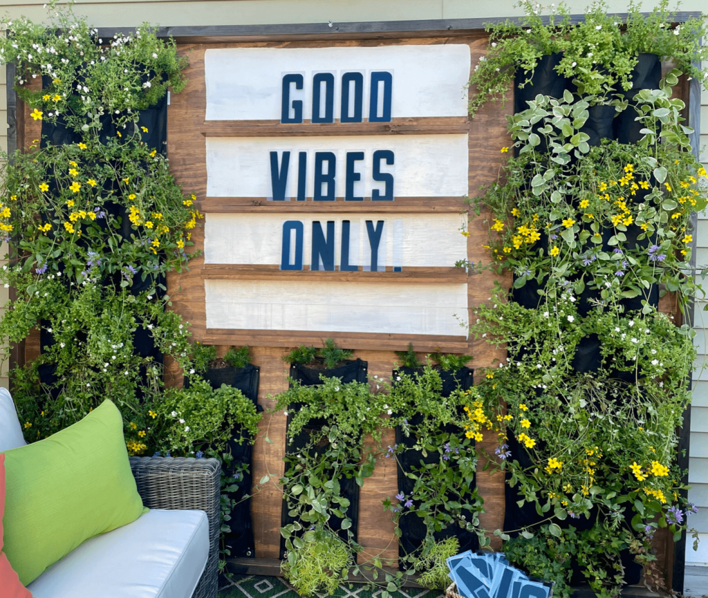 Letter board saying Good Vibes Only. With outdoor plant wall.