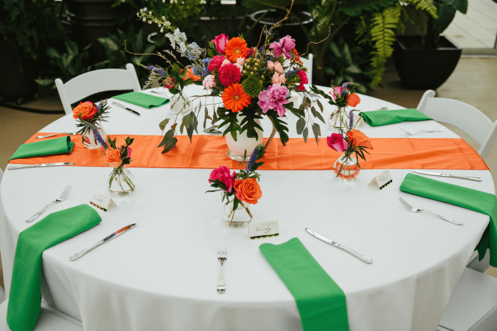 Table setting featuring bright colored linens and flowers
