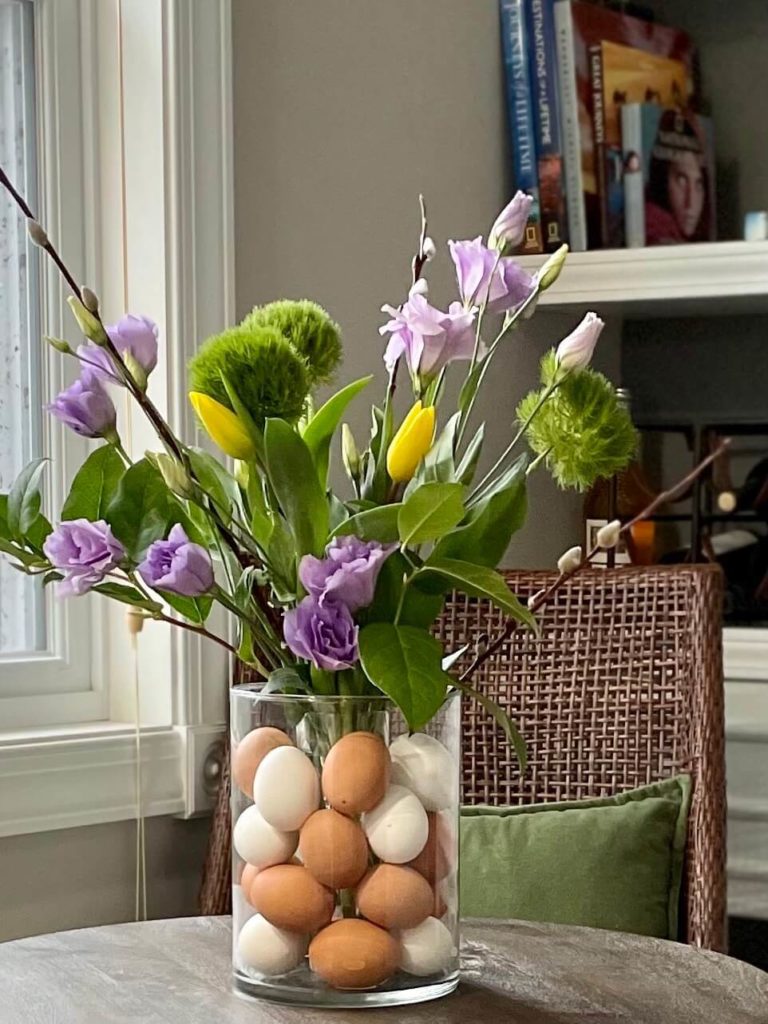 Fresh Flowers and Easter eggs arrangement in hurricane vase