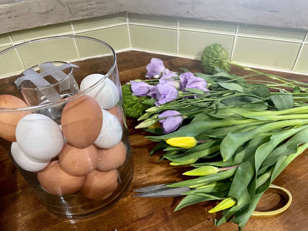 Preparing to assemble Sprint table arrangement with fresh flowers and Easter eggs.