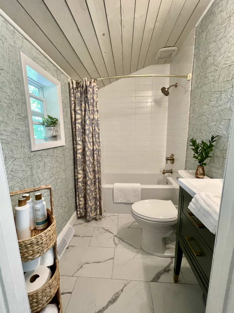 Cottage-style bathroom with green vanity and textured wallpaper.