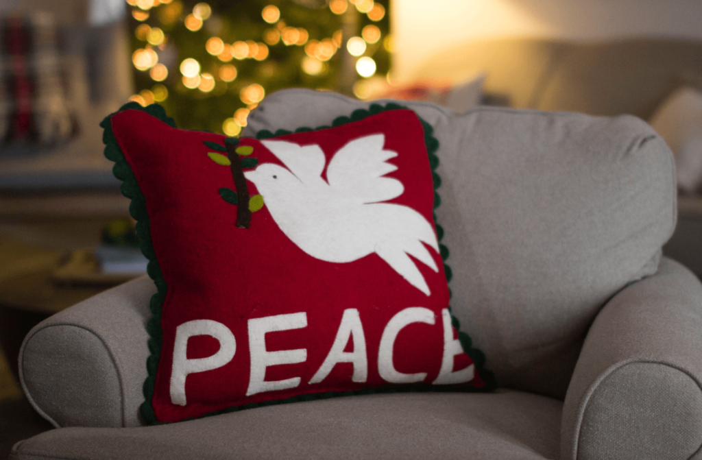 Cream chair with a red pillow that says "PEACE".