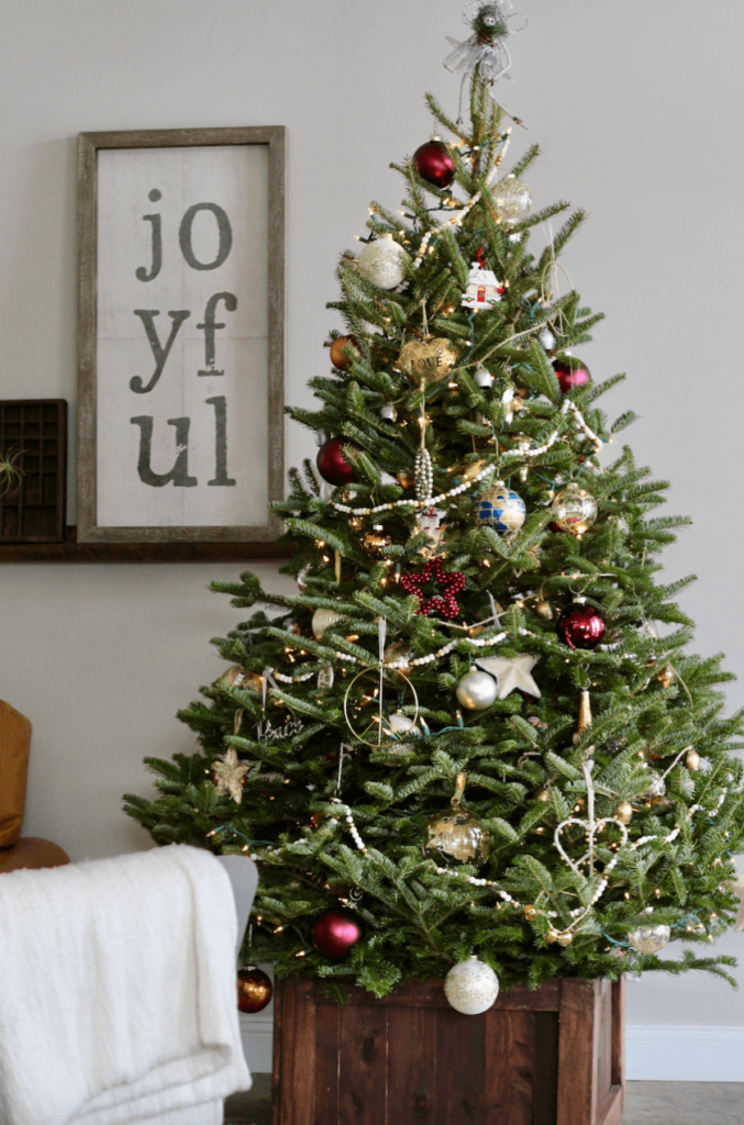 Live Christmas Tree featuring simple and neutral decorations and Holiday wall art that says "Joyful"