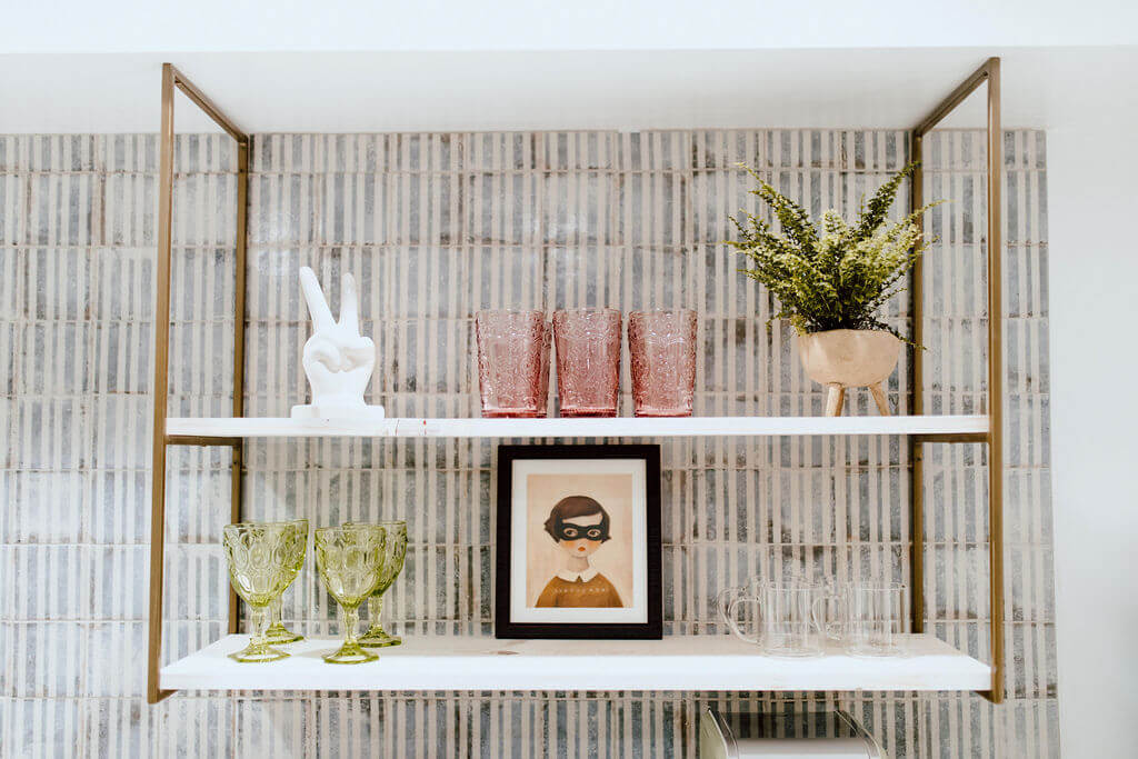Brass open shelving styled with glasses and plant in a modern cottage kitchen.