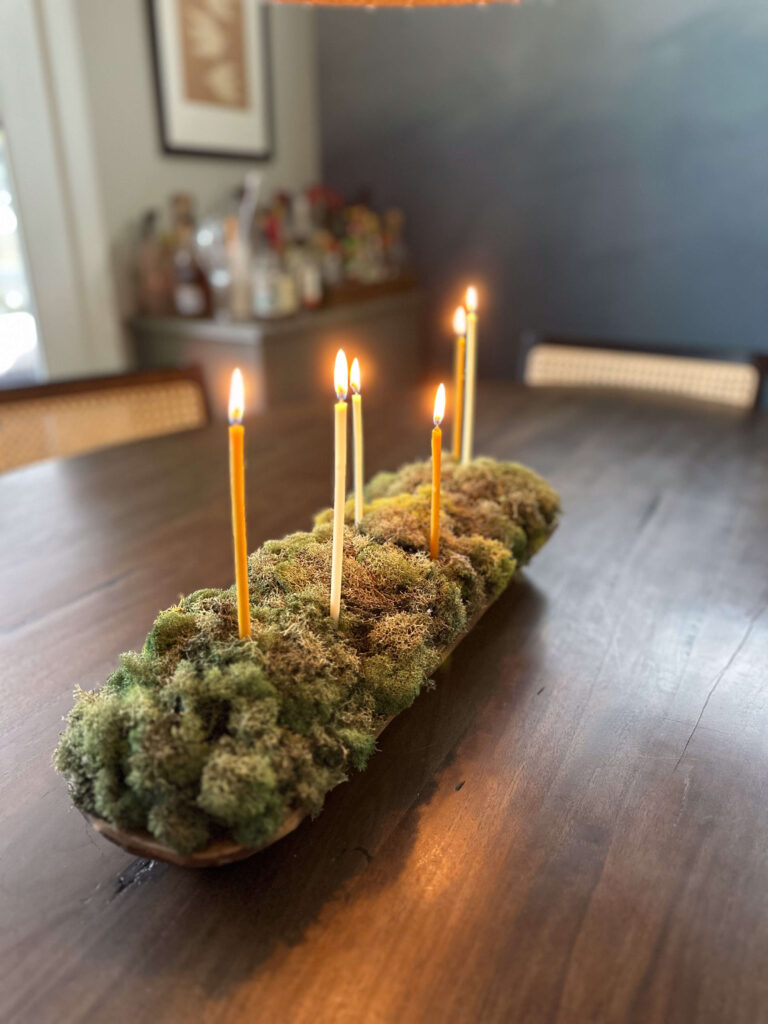 13 ideas for Natural Christmas. Moss in a dough bowl with moss and skinny candles on a brown oval dining table.