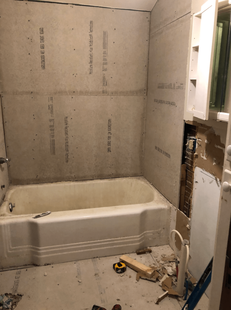 Before pic of a small bathroom reno showing a cast iron tub.