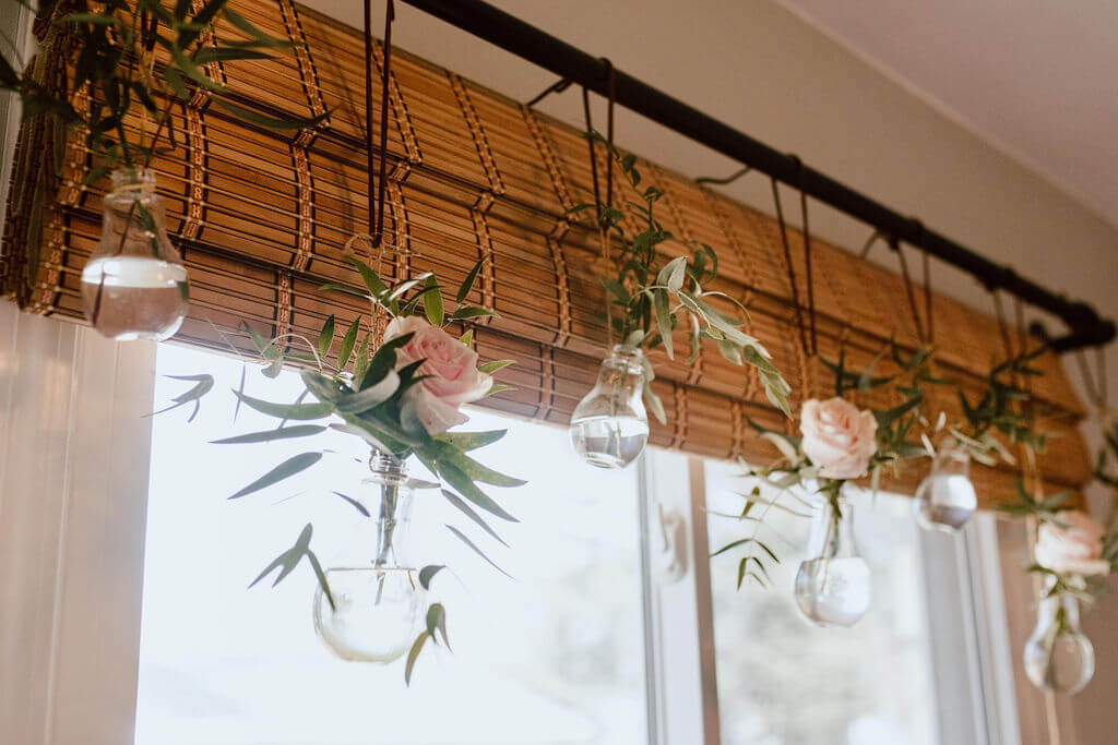 Fresh flowers in bud vases act as a window valance adding a cozy vibe. 