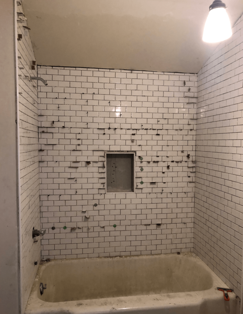 Small bathroom Renovation with shower being tiled in white classic subway tile with grey grout.