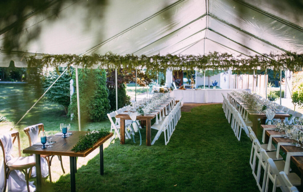 Tent with chairs and tables for an outdoor wedding reception.