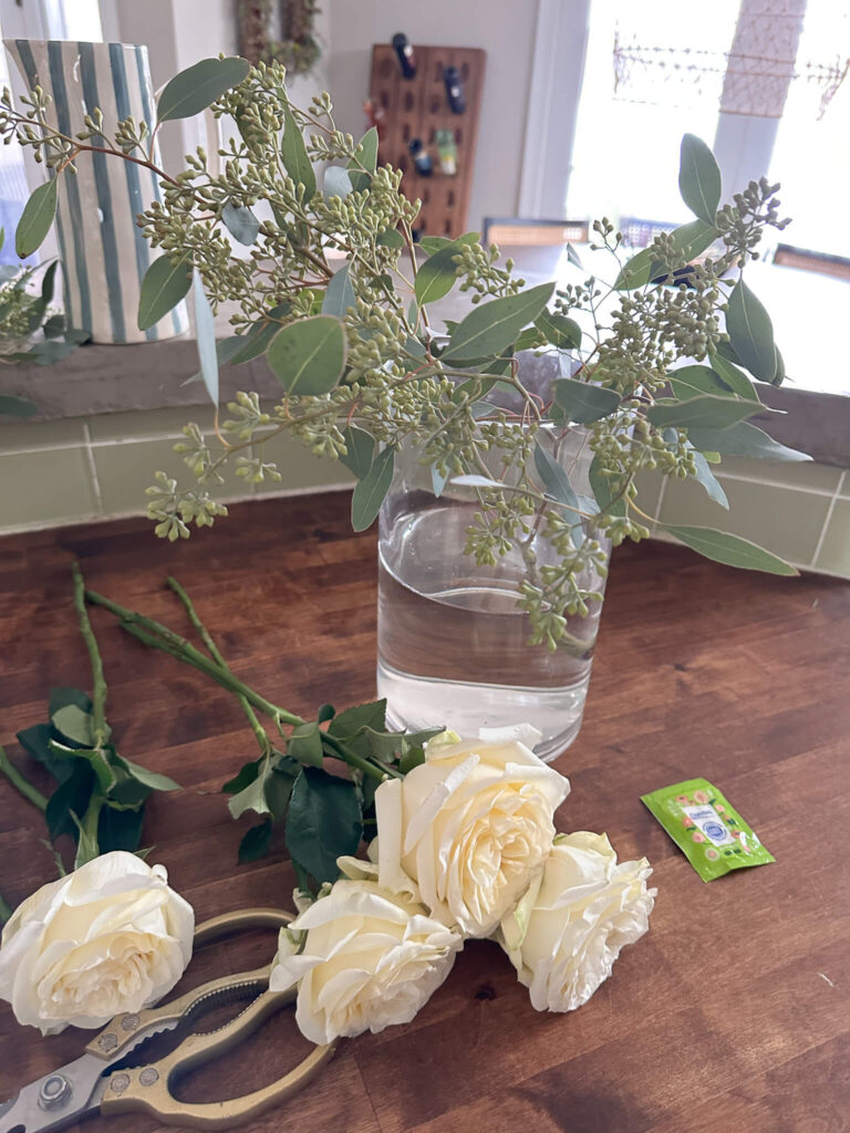 White flowers and seeded eucalyptus in a glass vase.
