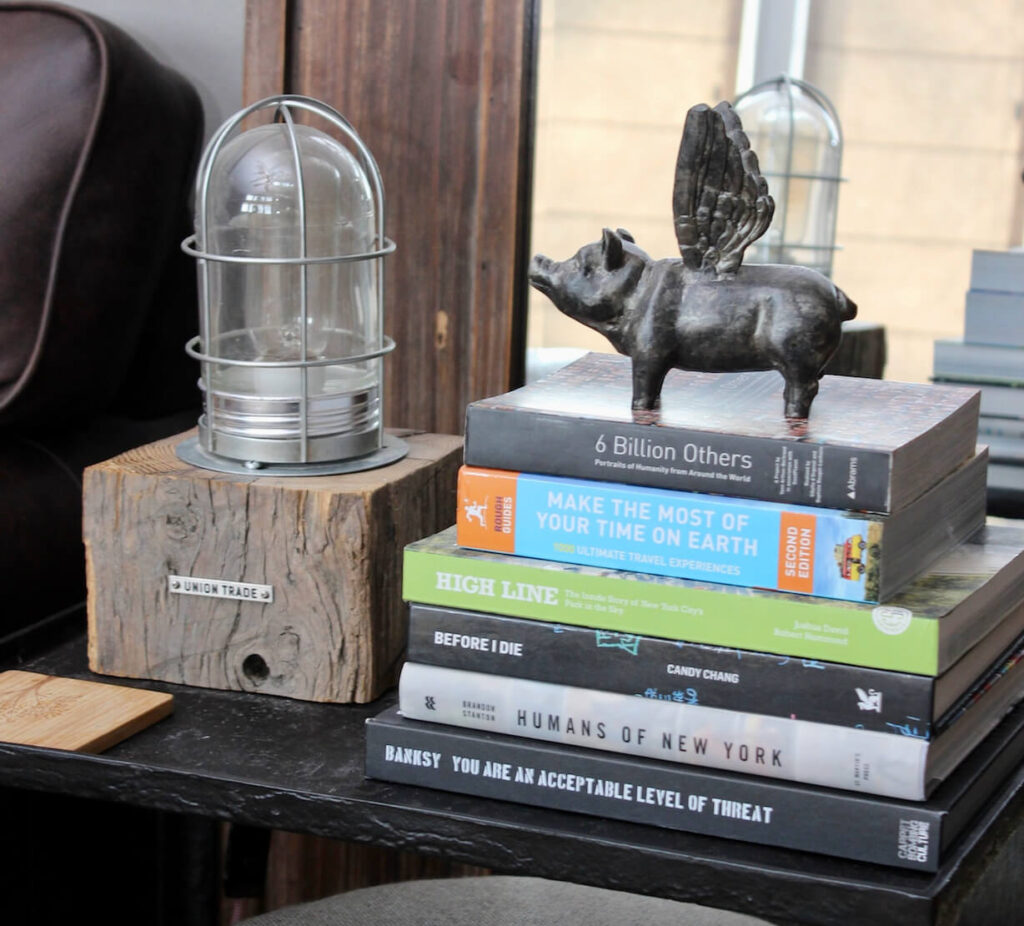 A side table with coffee table books and a small vintage lamp.