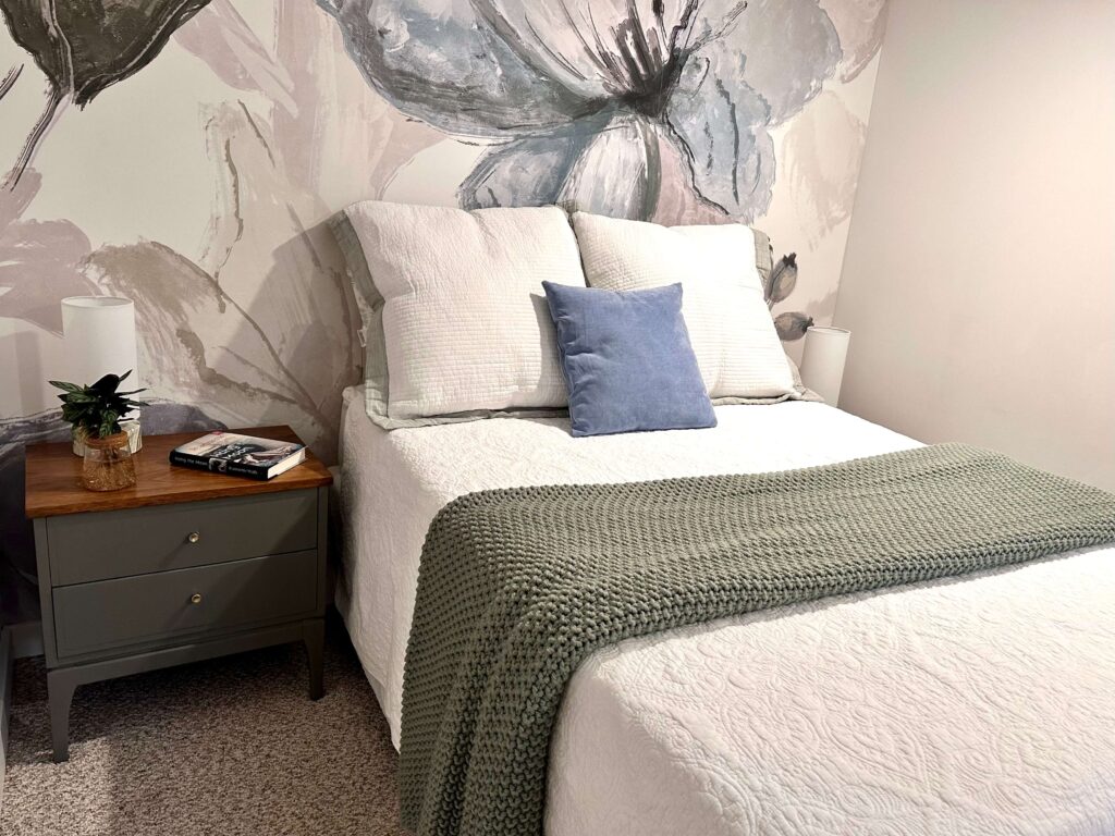 Bed with white layered bedding and a bold wallpaper mural.