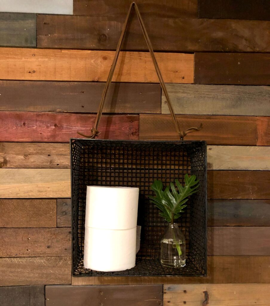 Black metal basket  a vintage find becomes a great way to store extra rolls of TP in a bathroom.