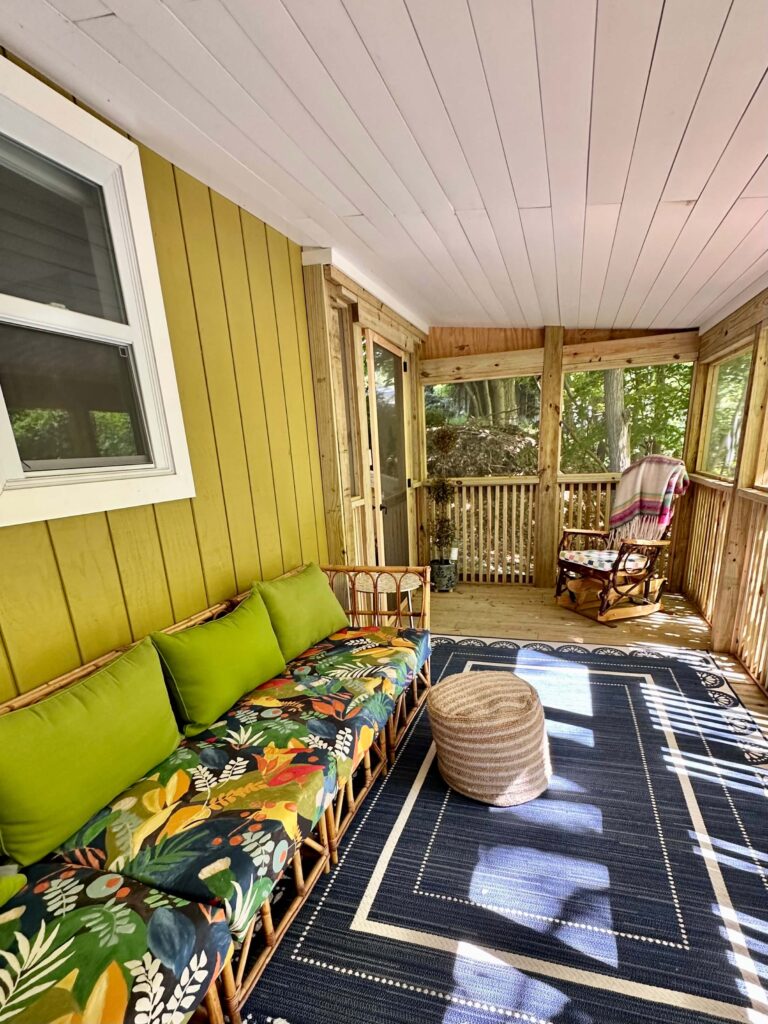brightly colored outdoor sofa on a screened in cottage porch