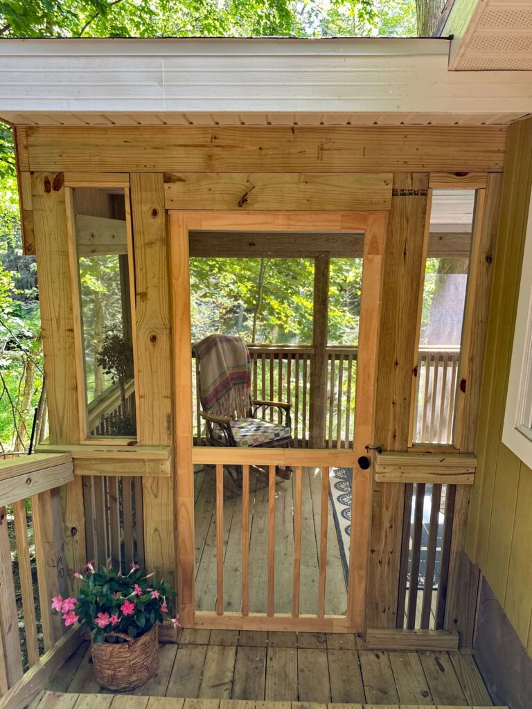 Wooden Door leading to screened in cottage porch.