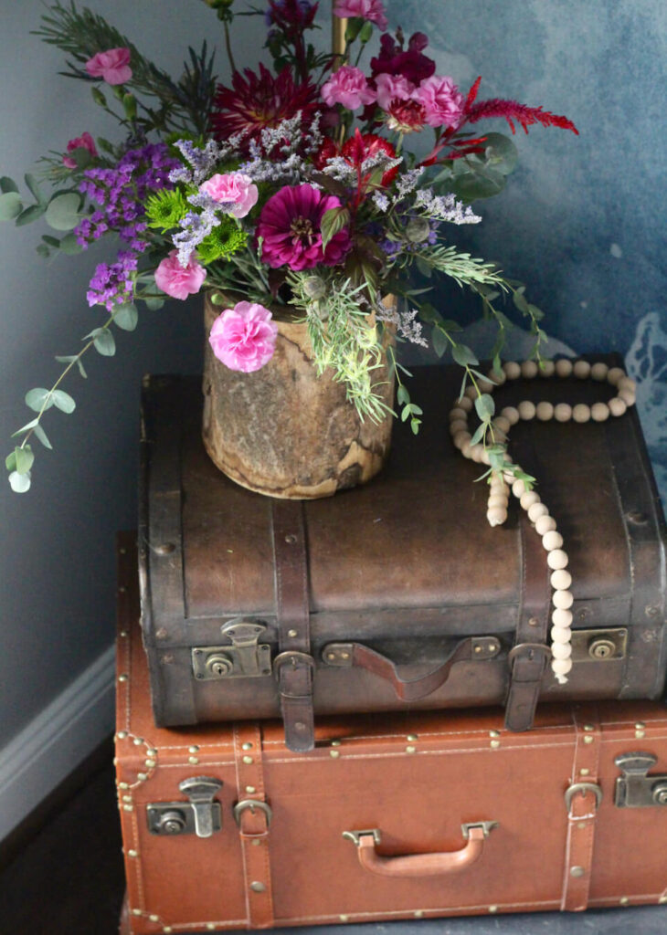 Stacked vintage suitcases as an nightstand in a cottagecore bedroom.