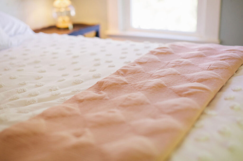 White cozy quilts in a cottagecore bedroom.