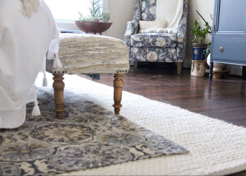 Cottagecore bedroom with layered rugs on a wood floor.