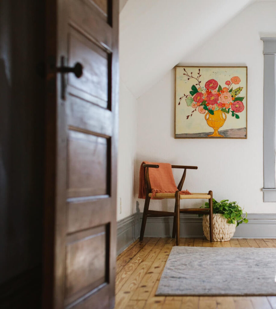 Pine floor with a rug and vintage door looking into a cottagecore bedroom.