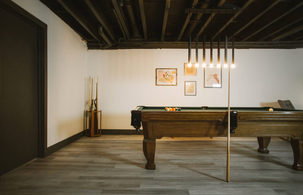 Renovated Basement featuring Peel and Stick Vinyl Flooring, Pool table and beautiful light fixture.