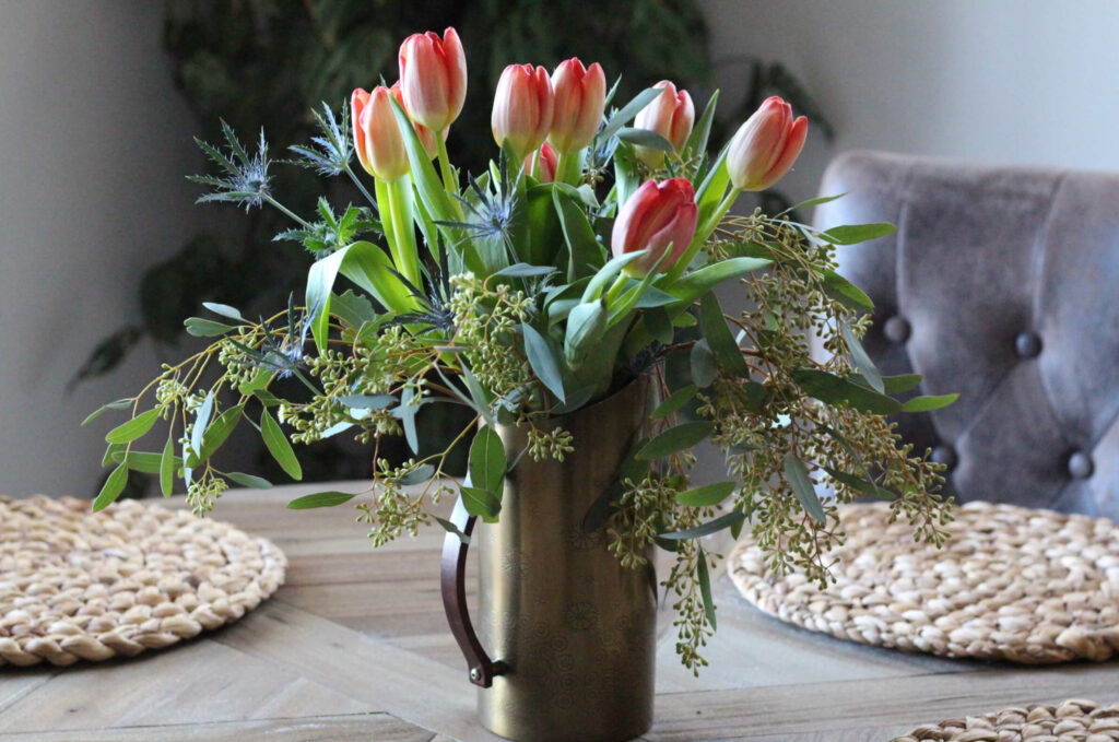 Copper Vase filled with orange tulips and eucalyptus.