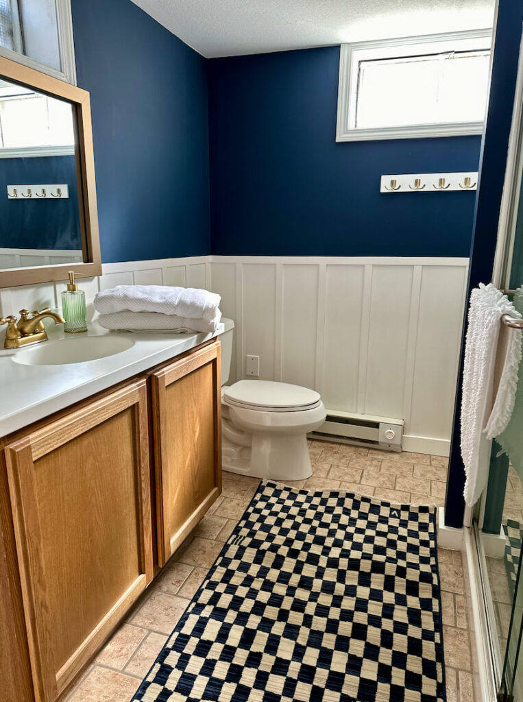 Bathroom updated with a wood accent wall (board and batten), Navy paint and a new mirror frame.