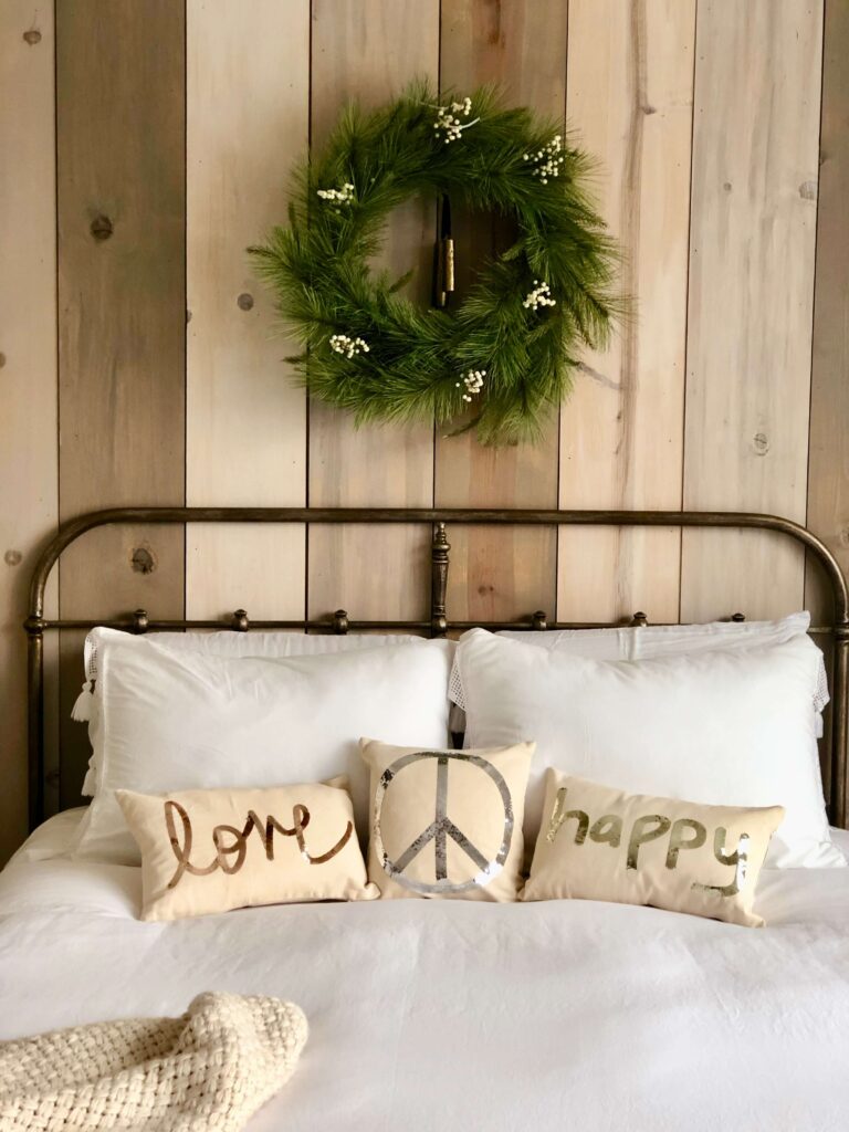 Bed made with Holiday pillows and a wreath.