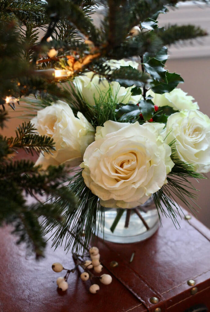 White roses for Christmas on a bedroom nightstand.