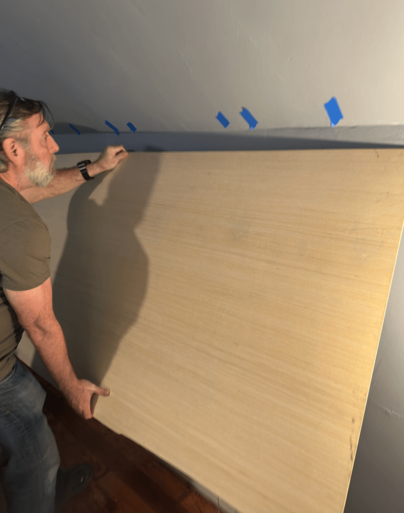 Man applying plywood to a wall.