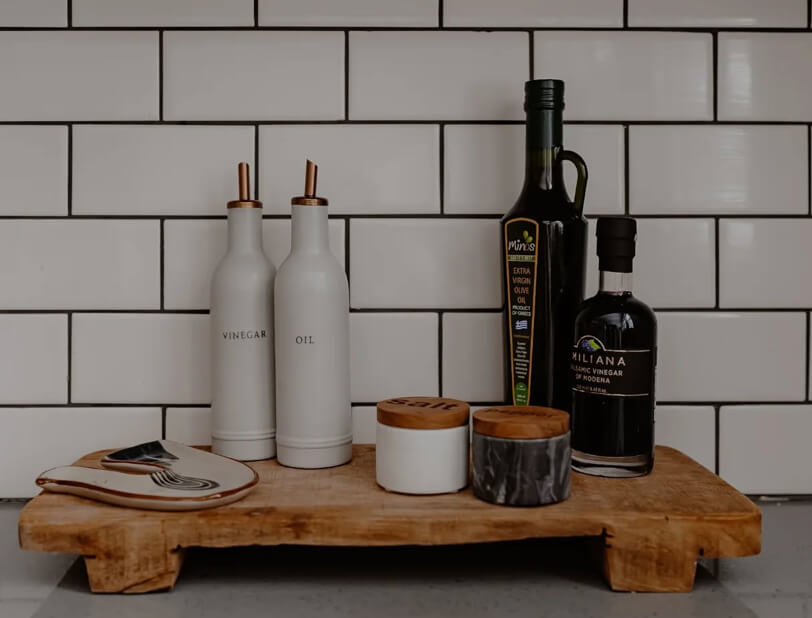 Wood Tray with oil and vinegar bottles and salt and pepper. In a White kitchen