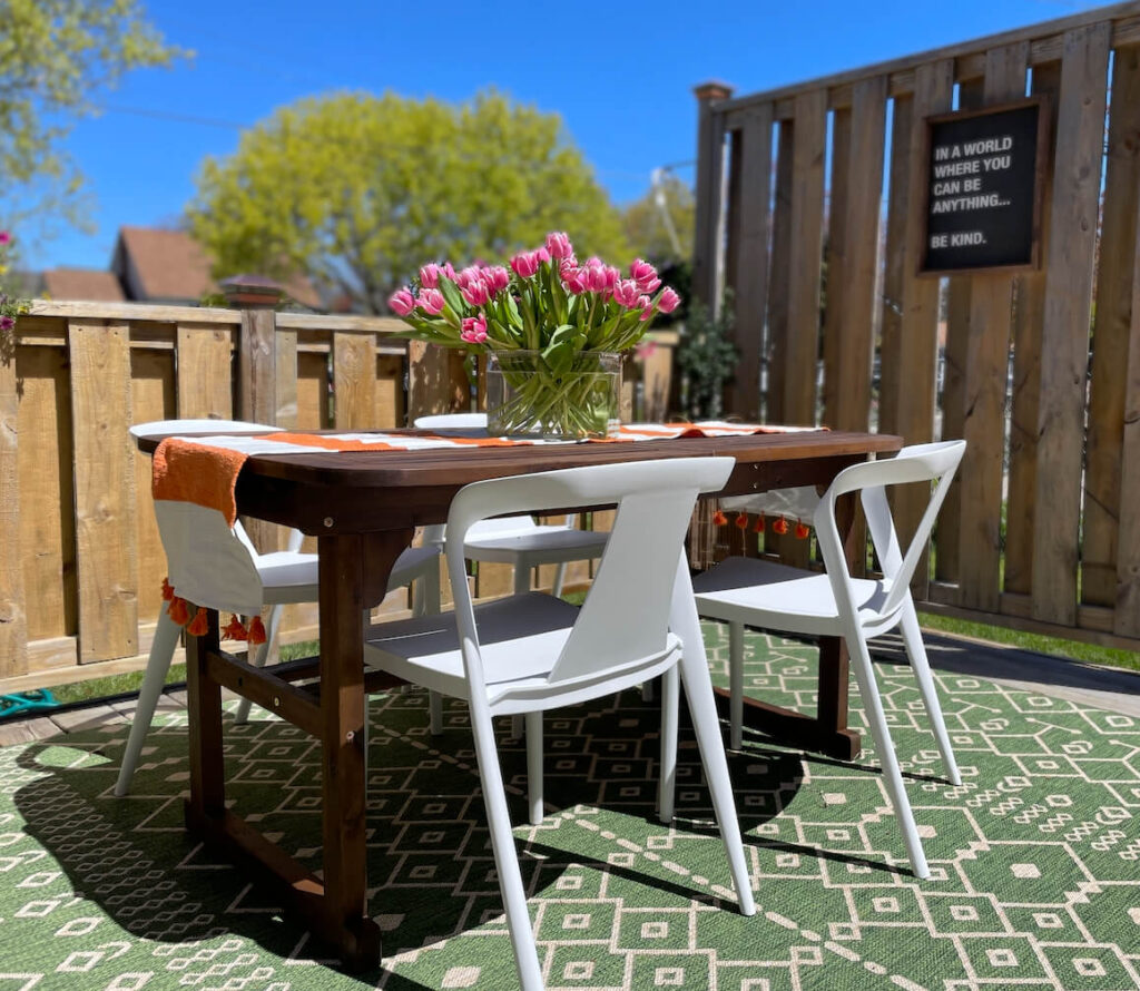 Outdoor dining table with white plastic chairs.