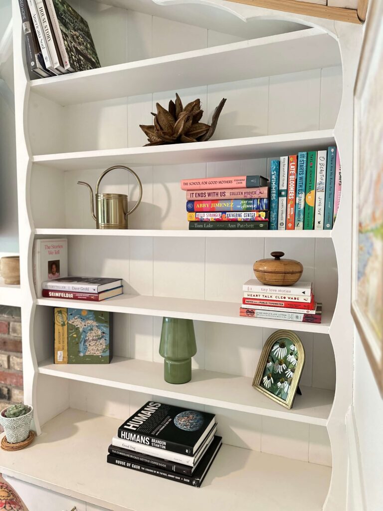 Cottage Bookshelf Filled With Coffee Table books at an Airbnb in Petwater, MI