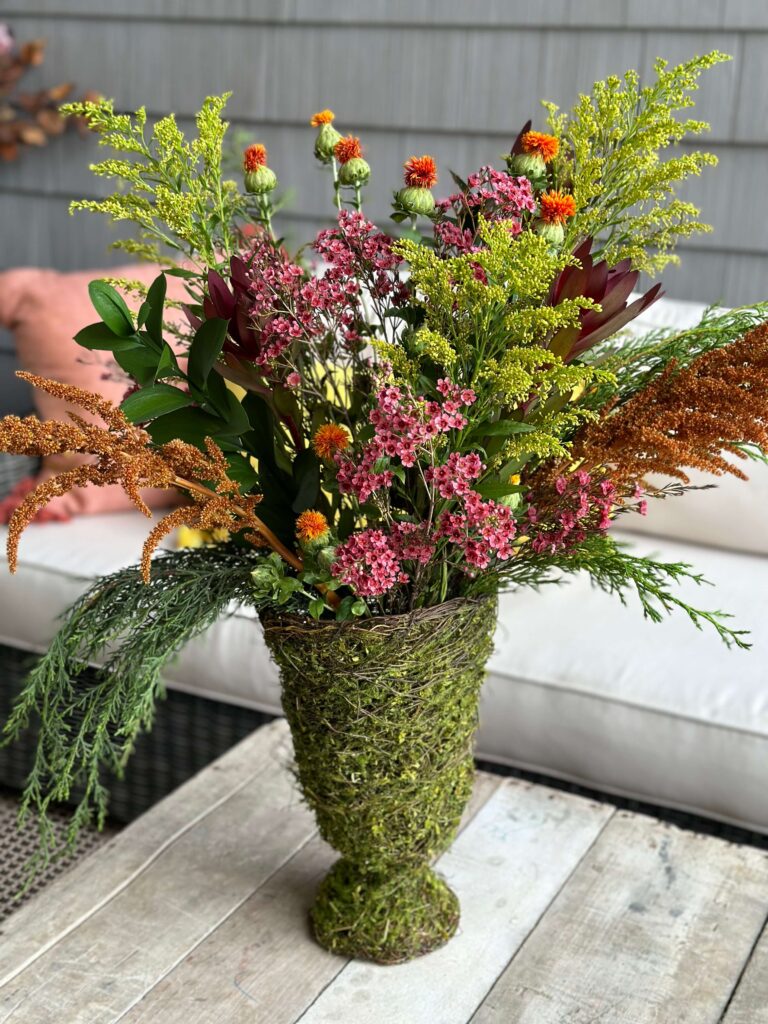 Fall Floral arrangement in a moss covered vase.