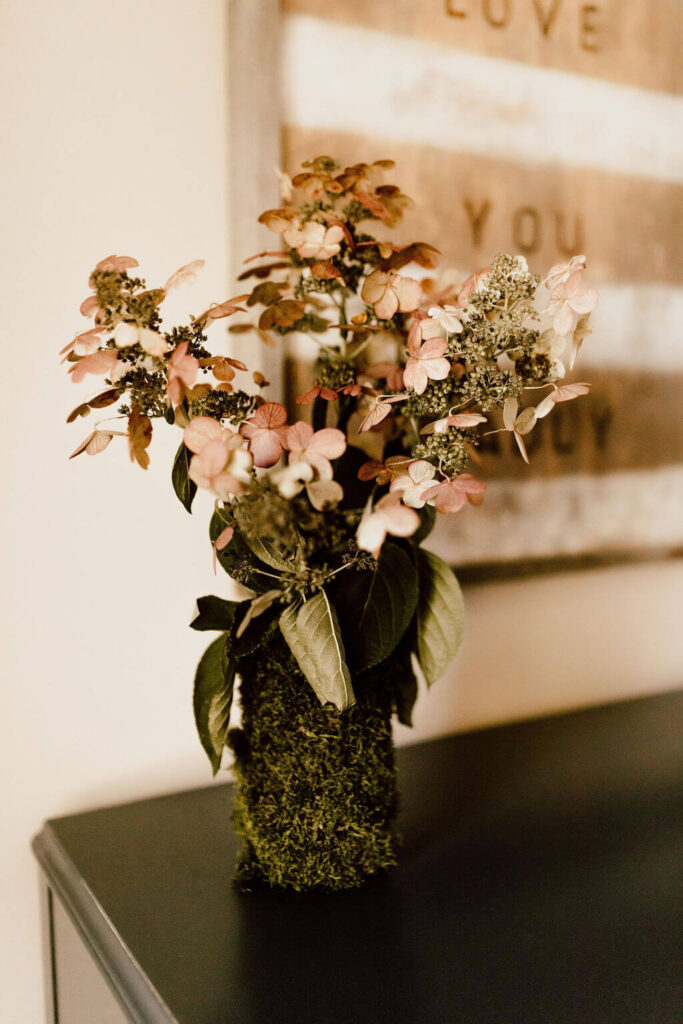 Hydrangea drying in a moss covered vase. Perfect for nature-inspired fall decor.