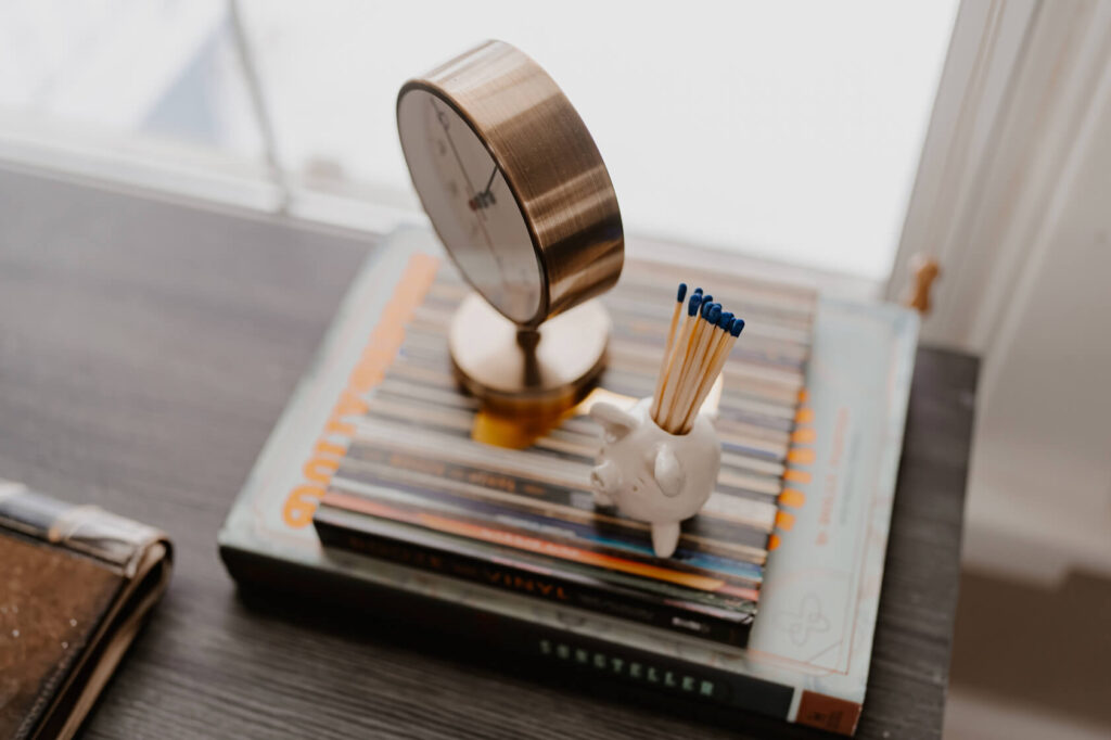Clock and match holder sitting on decor books on desk.