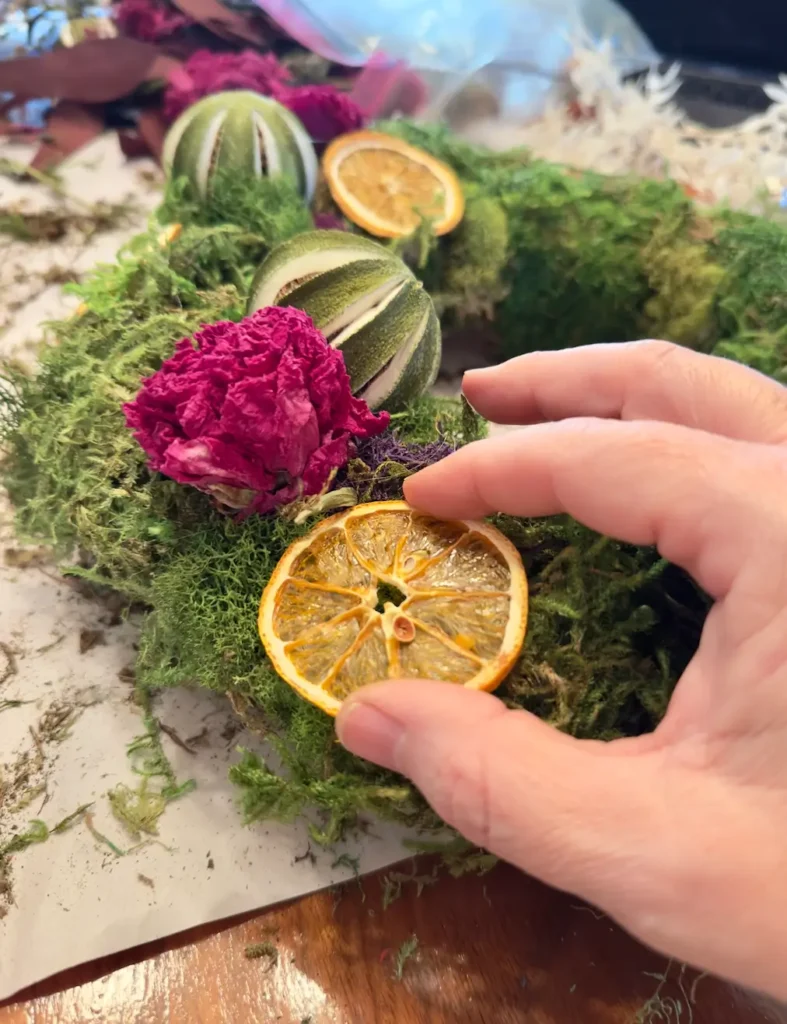 Making a Christmas Wreath with dried fruit and flowers.