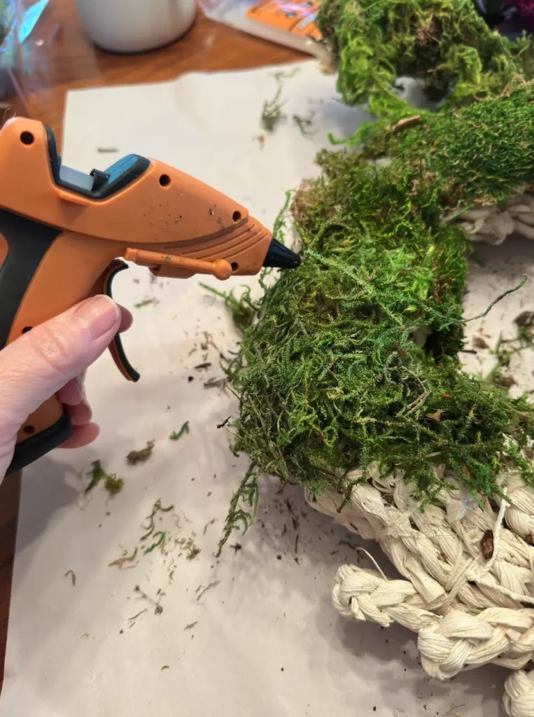 Gluing moss to a wreath.