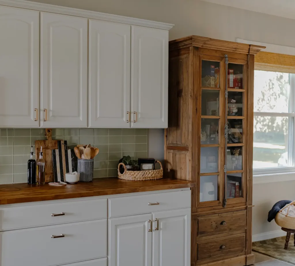 Wood pantry cabinet added to the end of white kitchen cabinets to add warmth.
