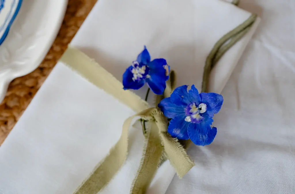 Scalloped Napkins tied with ribbon and Delphiniums.